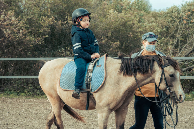 Girl sitting on horse against trees