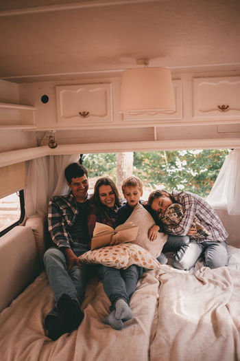 Happy family on camping trip relaxing in the autumn forest camper trailer. fall season outdoors trip