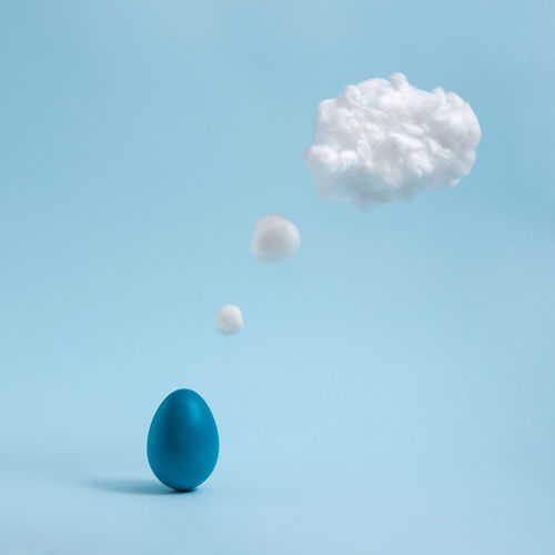 Blue easter egg is thinking. cotton made cloud like thought ballon. pastel blue background. abstract