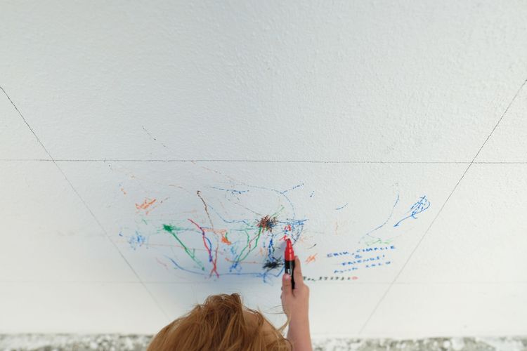 High angle view of cute boy drawing on wall outdoors