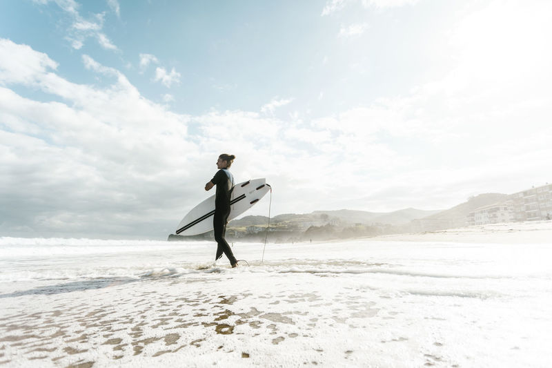 Surfer entering the water in the basque country, spain, bilbao