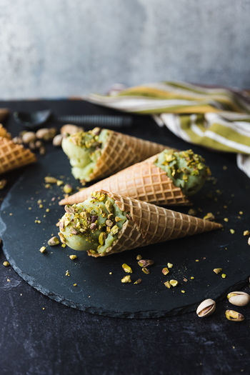 Close up of pistachio ice cream in cones on black background.