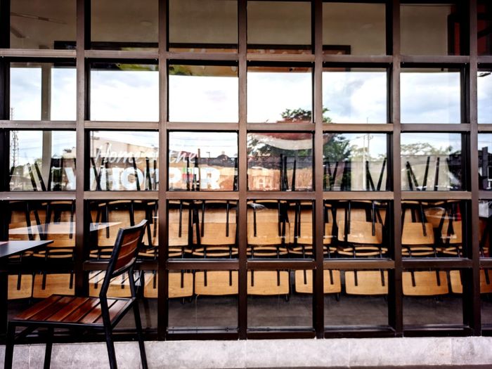 Empty chairs and tables in glass window