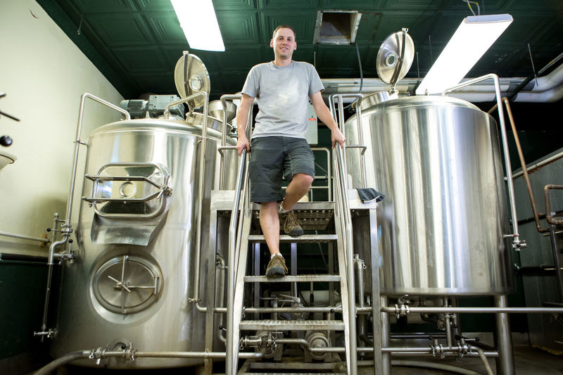 Low angle portrait of brewery worker standing by fermentation tanks