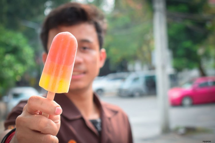 Portrait of man holding popsicle in city