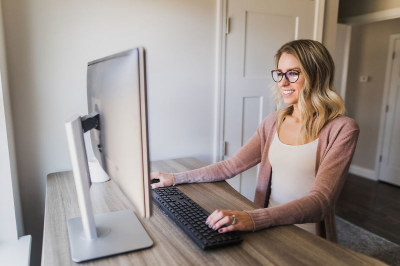 Smiling businesswoman using computer while sitting on table at home