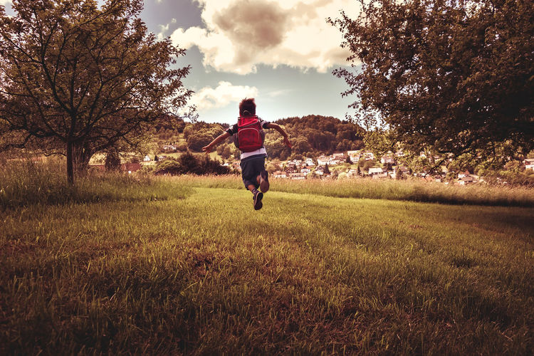 Rear view of boy jumping over grass