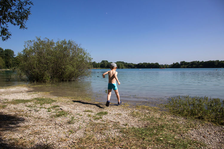 Full length of boy running against lake