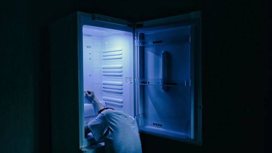 Man sleeping in refrigerator at home