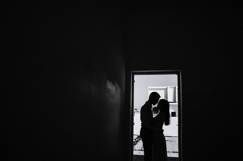 Silhouette couple romancing while standing in darkroom at home