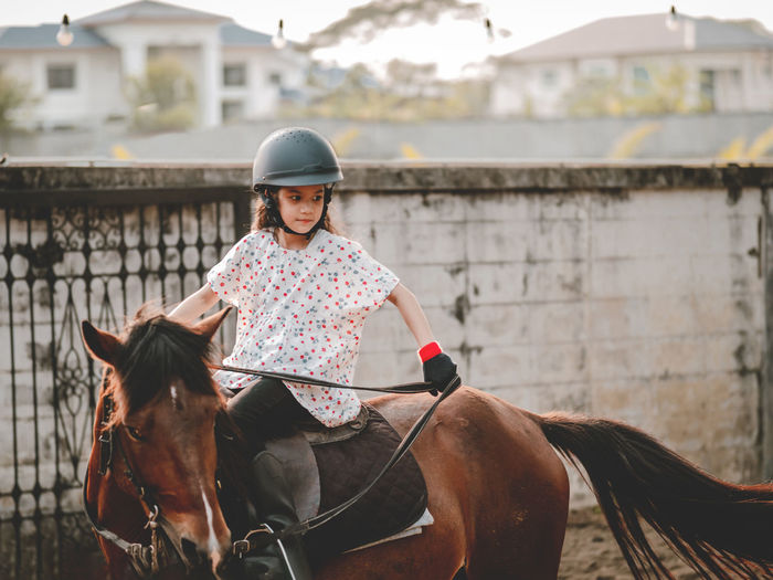 Aisan school kid riding or practicing horae at horse ranch