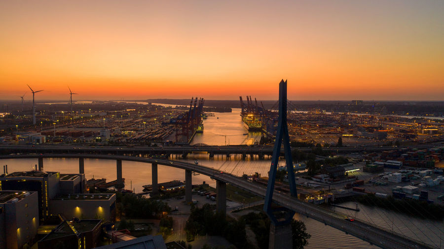 High angle view of bridge over river by buildings against sky during sunset