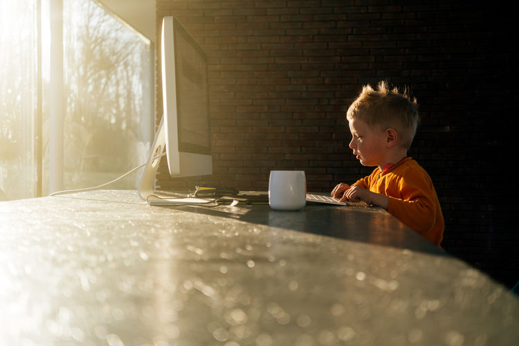 Side view of boy using computer on table