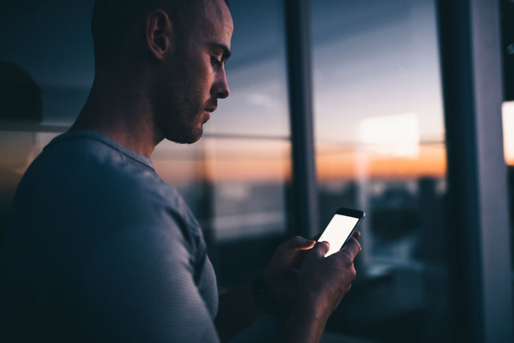 Close-up of man using mobile phone at sunset
