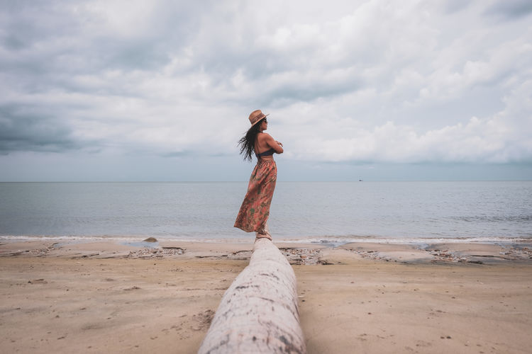 Woman standing at beach against sky