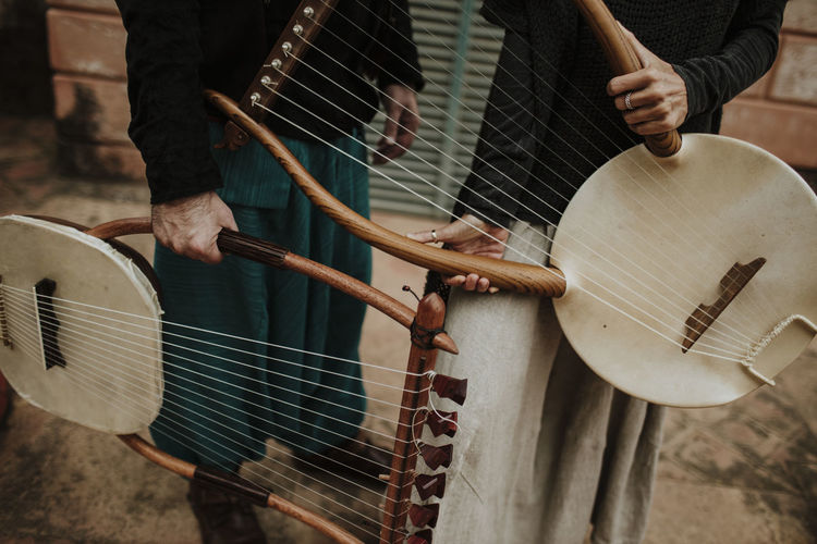 Male and female holding lyra musical instrument outdoors