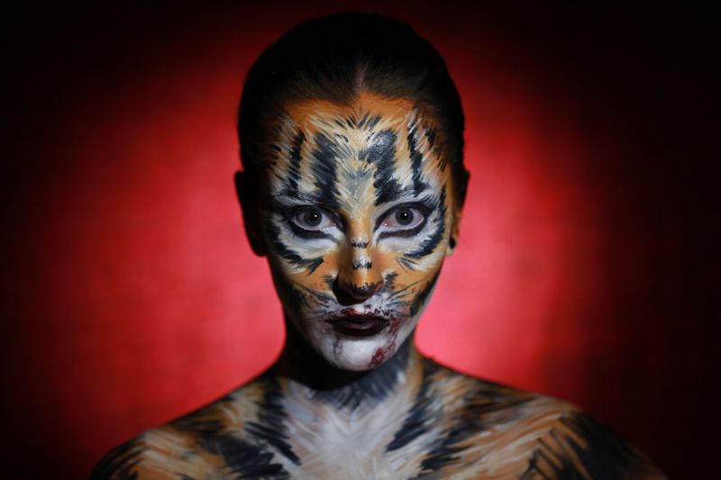 Portrait of young woman with face paint against colored background