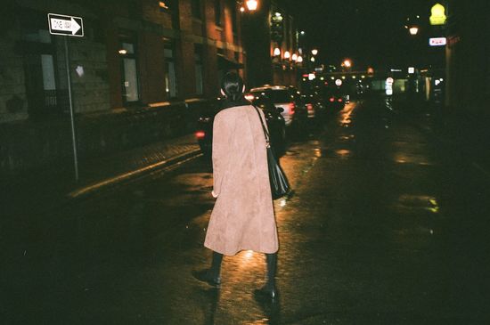 REAR VIEW OF WOMAN WALKING ON STREET IN CITY