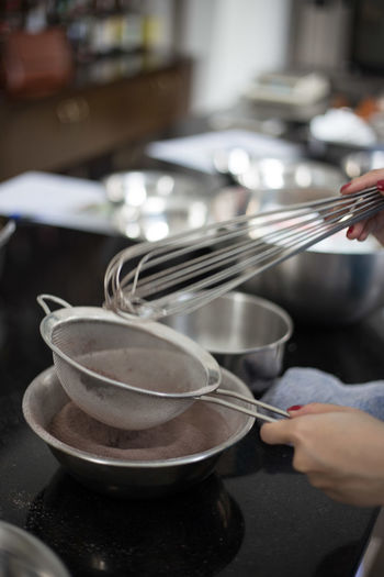 Cropped image of woman holding wire whisk while baking in kitchen