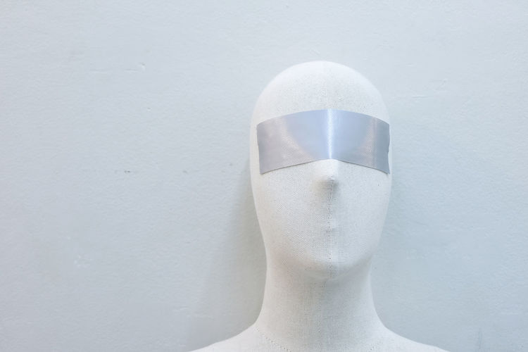 Close-up of mannequin with blind fold against wall