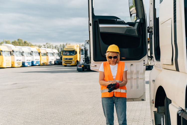 Female trucker standing by truck