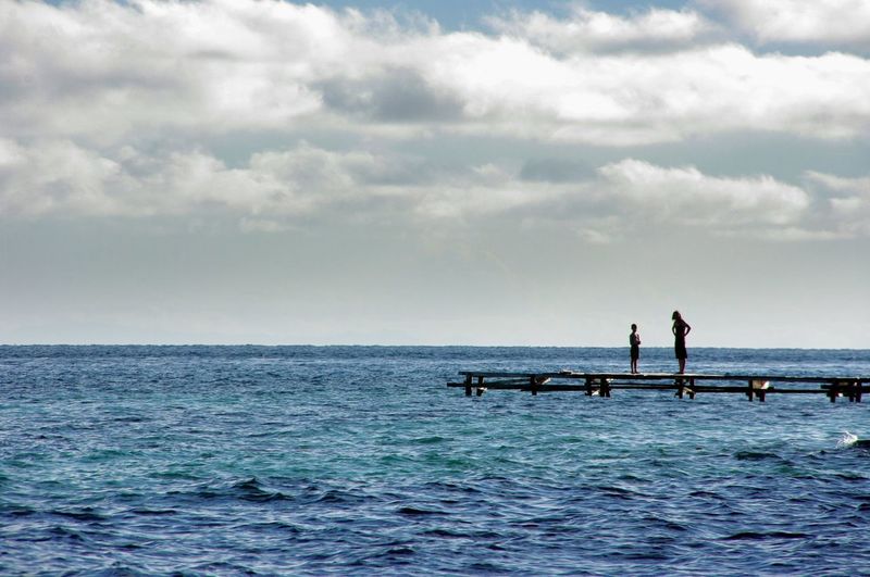 People standing on pier over sea against sky