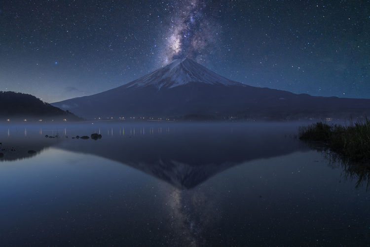 Scenic view of lake and mountains against sky at night