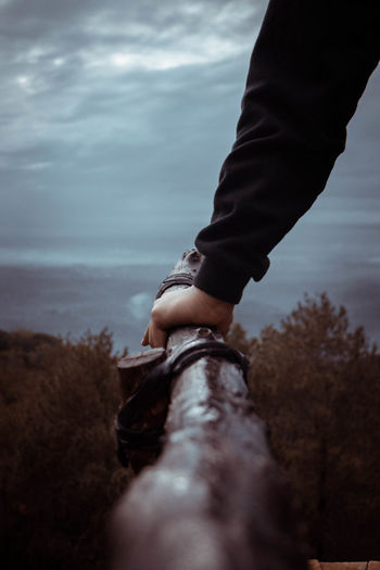 Close-up of hand holding wood against sky