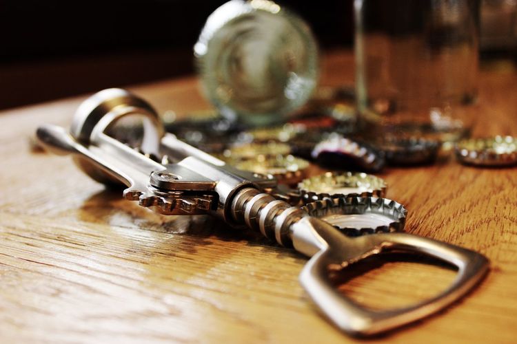 Close-up of bottle opener and caps on table