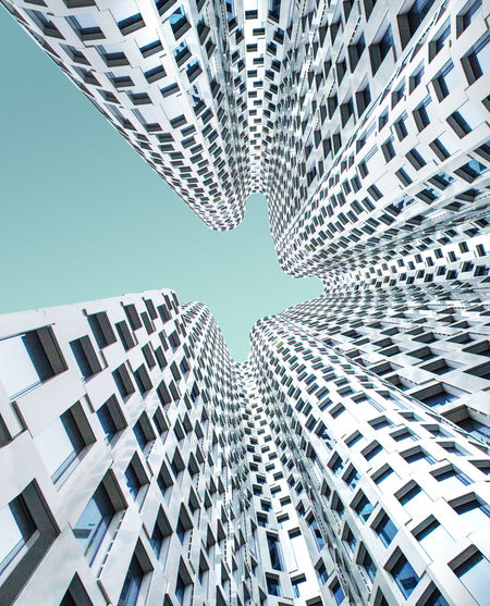 Directly below shot of modern buildings against blue sky