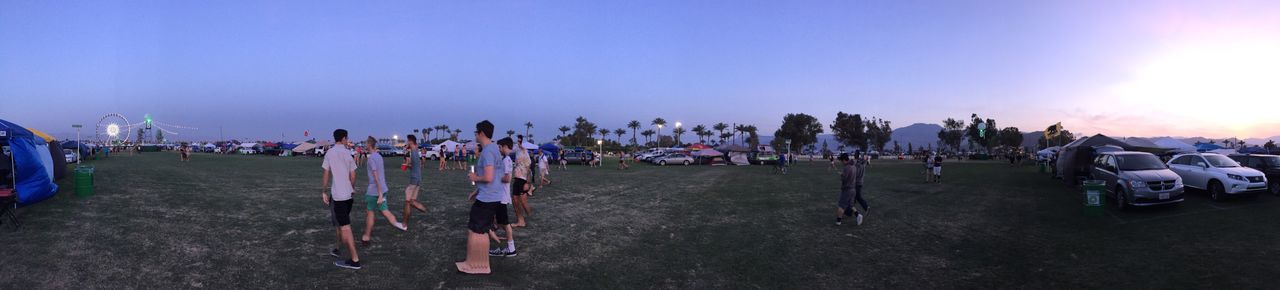 Panoramic view of people walking on field against sky at dusk