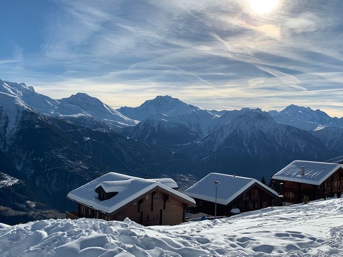 Snow covered houses and mountains against sky