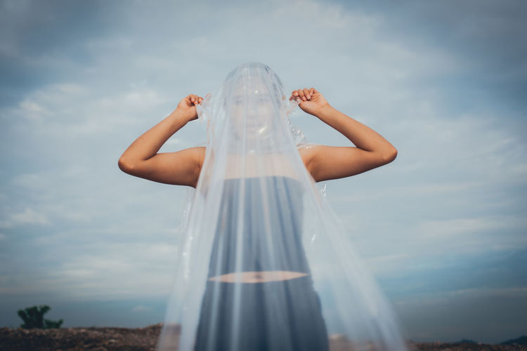 Woman wearing plastic while standing against sky