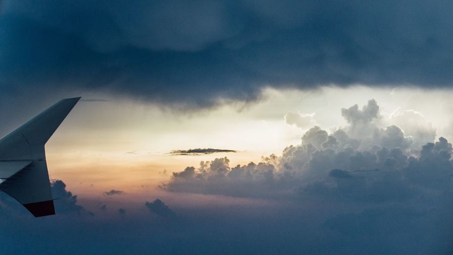 View of airplane wing against cloudy sky
