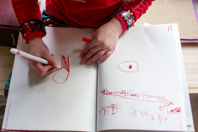 Above view of a little girl drawing pictures with a red marker