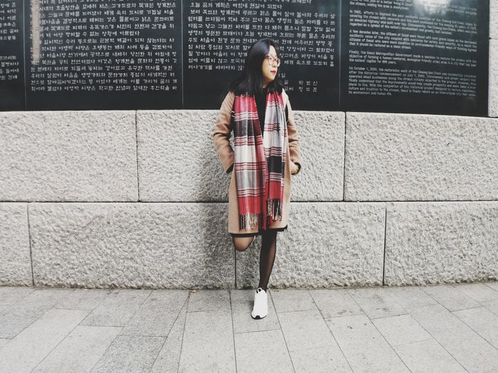 Portrait of woman standing against wall