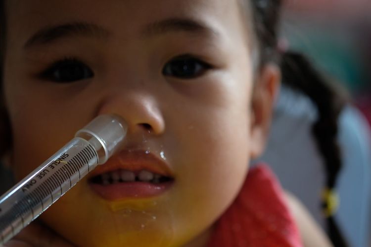 Close-up portrait of girl with syringe in nose
