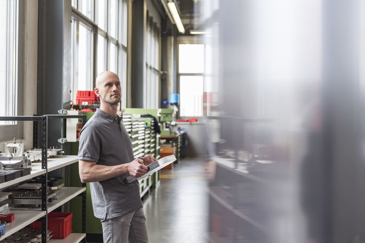 Man standing in modern factory holding product