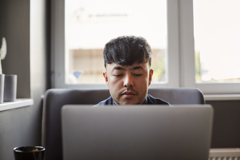 Portrait of young man using laptop at office