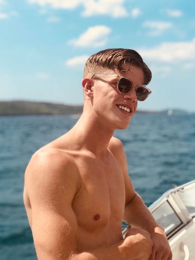 Shirtless young man in boat against sea
