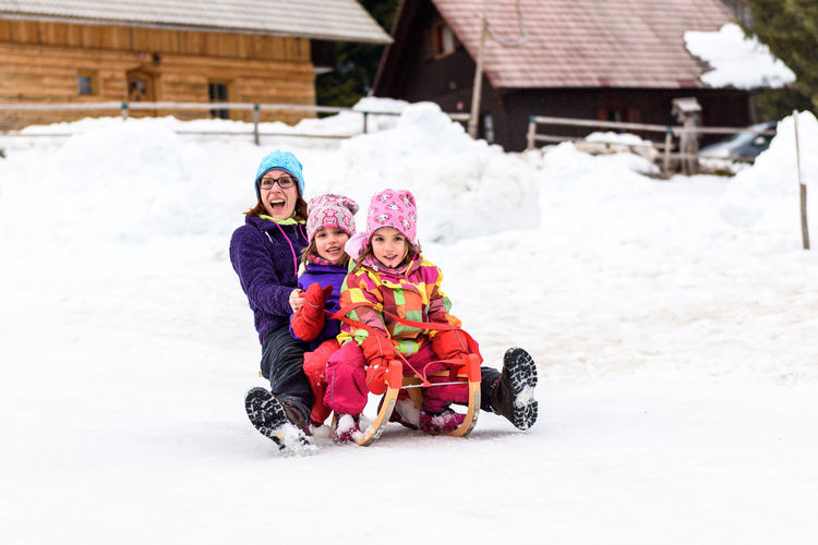 Portrait of happy family sledding on snow