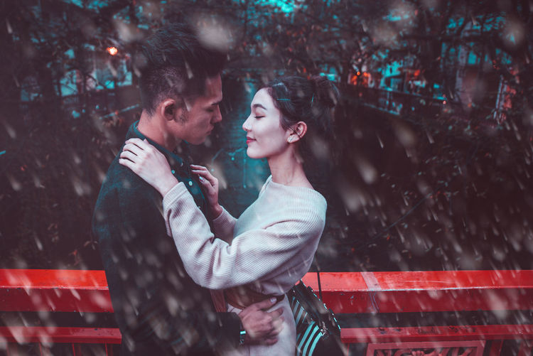 Side view of couple embracing while standing outdoors in rain