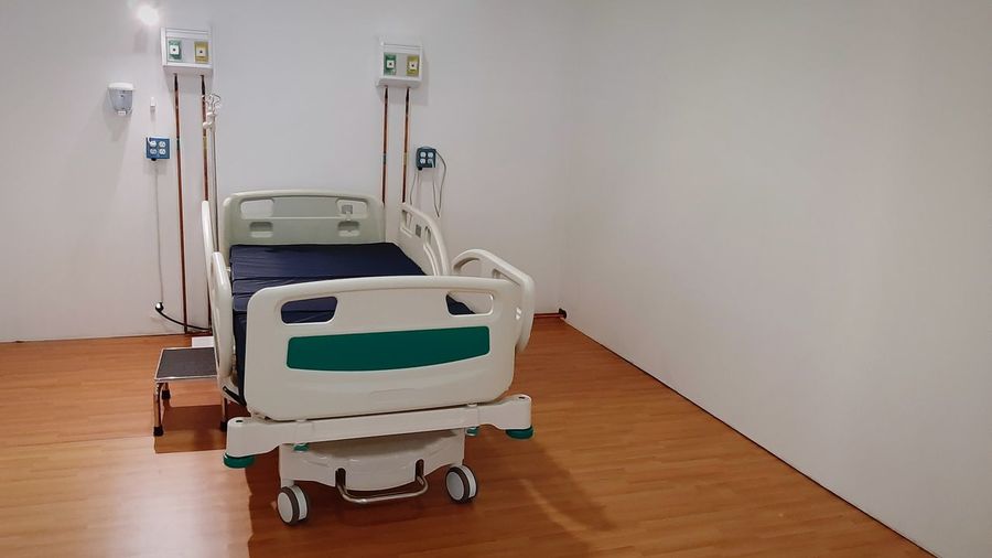 Empty bed on hardwood - material floor against wall in hospital