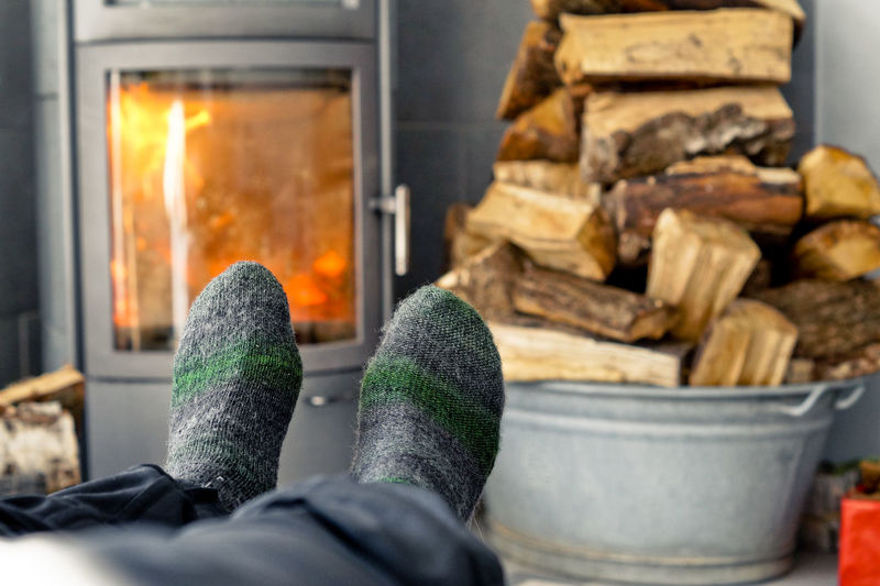 Low section of man wearing socks against firewood stack