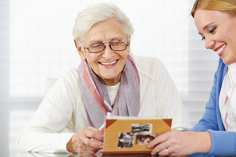 Smiling nurse holding photo album by woman on table