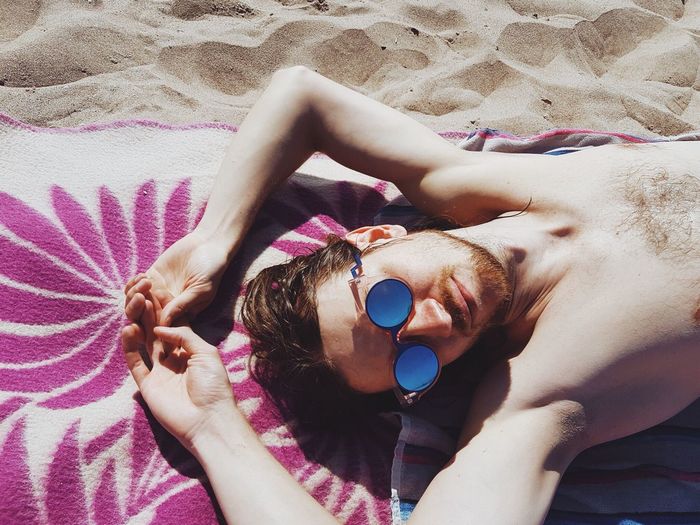 Directly above shot of young man lying on sand at beach
