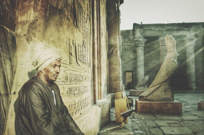 Thoughtful mature man sitting by temple of edfu