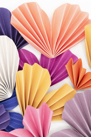 Many homemade colorful paper hearts arranged on white background