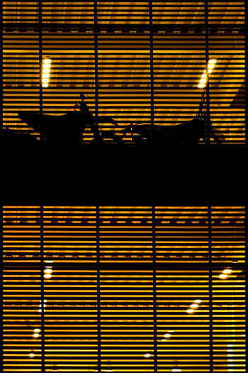 Silhouette motorcycles in illuminated orange parking garage seen from window