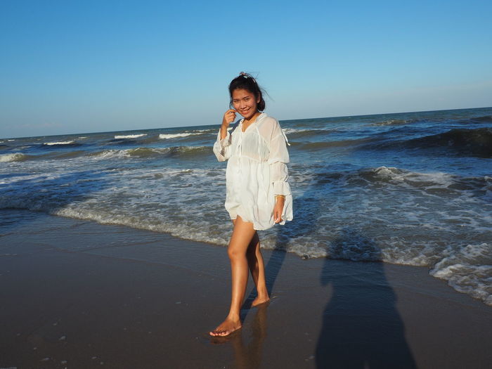 Woman standing at beach against sky